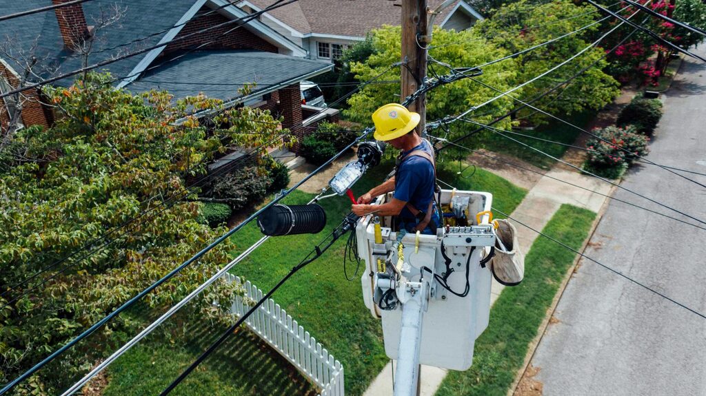 un électricien dans une nacelle qui travail sur des lignes électriques